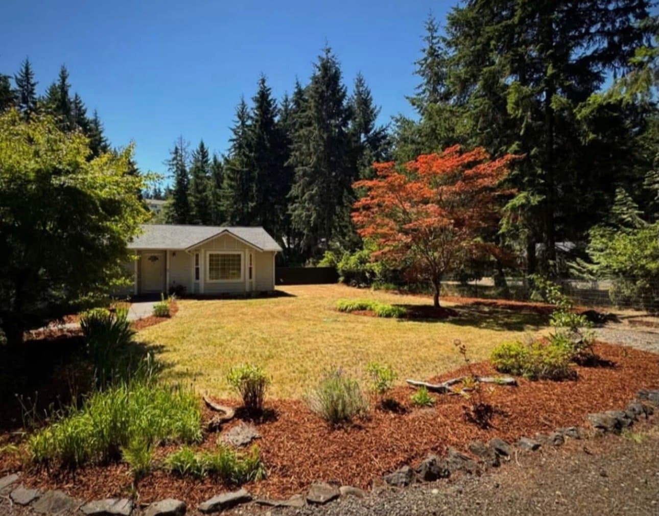 Home with mulch beds, decorative rock border, and a Japanese maple